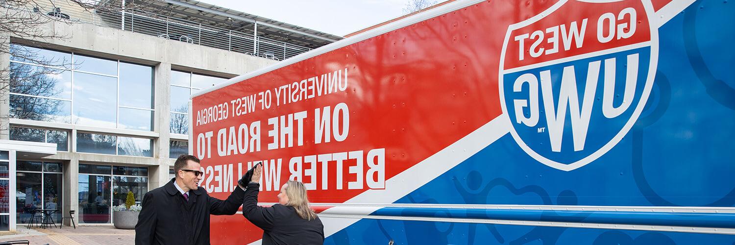 在线博彩 President 布伦丹·凯利 and Chief Wellness Officer Bridgette Stewart high five in front of 在线博彩's mobile unit